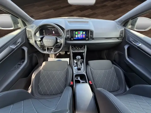 Vue intérieure avant du Skoda Karoq noir 2025, tableau de bord moderne avec écran tactile central et volant cuir multifonctions.
