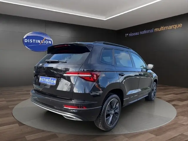 Vue 3/4 arrière droite d'un Skoda Karoq noir 2025 avec feux LED et jantes alliage sombres.