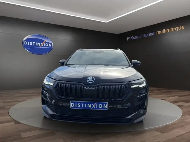 Vue frontale d'un Skoda Karoq noir 2025 avec calandre noire et feux LED, présenté en showroom Distinxion.