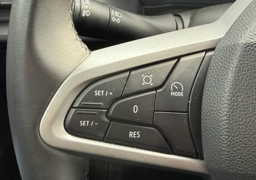 Gros plan sur les commandes multifonctions côté gauche du volant du Dacia Duster 2025 couleur Sandstone.