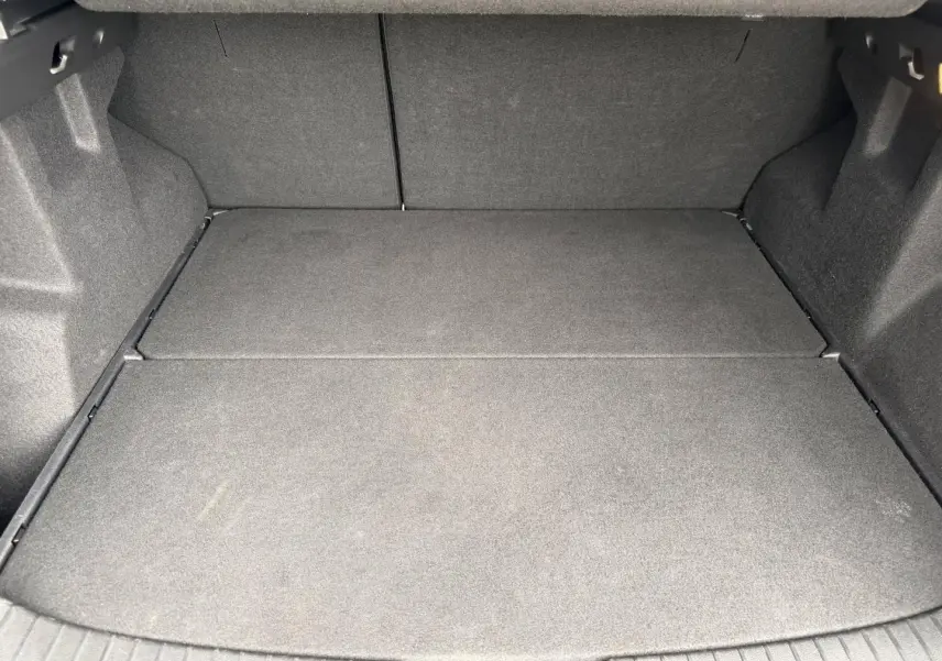 Coffre spacieux du Dacia Duster 2025, vue intérieure arrière, revêtement tissu gris foncé uniforme.