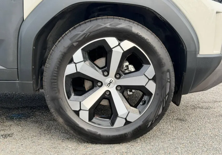 Gros plan sur la roue avant droite du Dacia Duster 2025 couleur Sandstone avec jante alu bicolore.