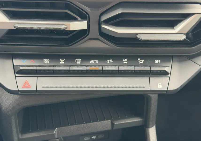 Vue rapprochée de la console centrale du Dacia Duster 2025 sandstone, avec commandes climatisation et prises USB visibles.