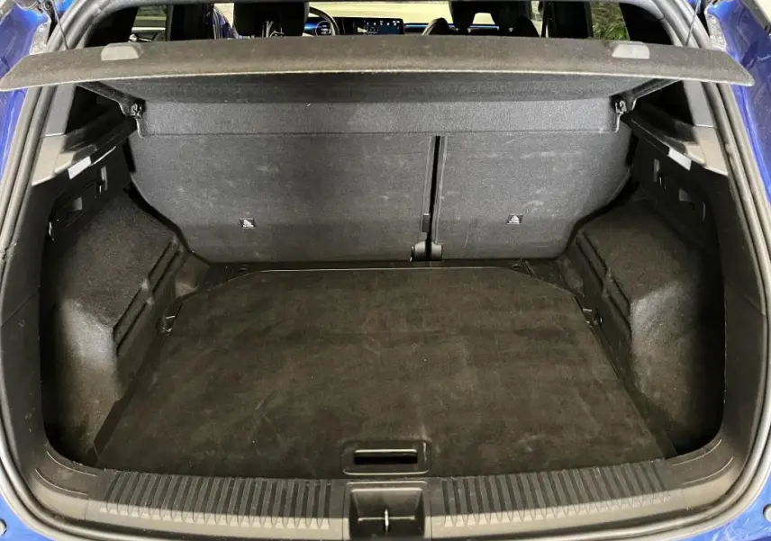 Coffre ouvert vu de l'arrière d'un Renault Austral bleu, avec cache-bagages et intérieur noir.