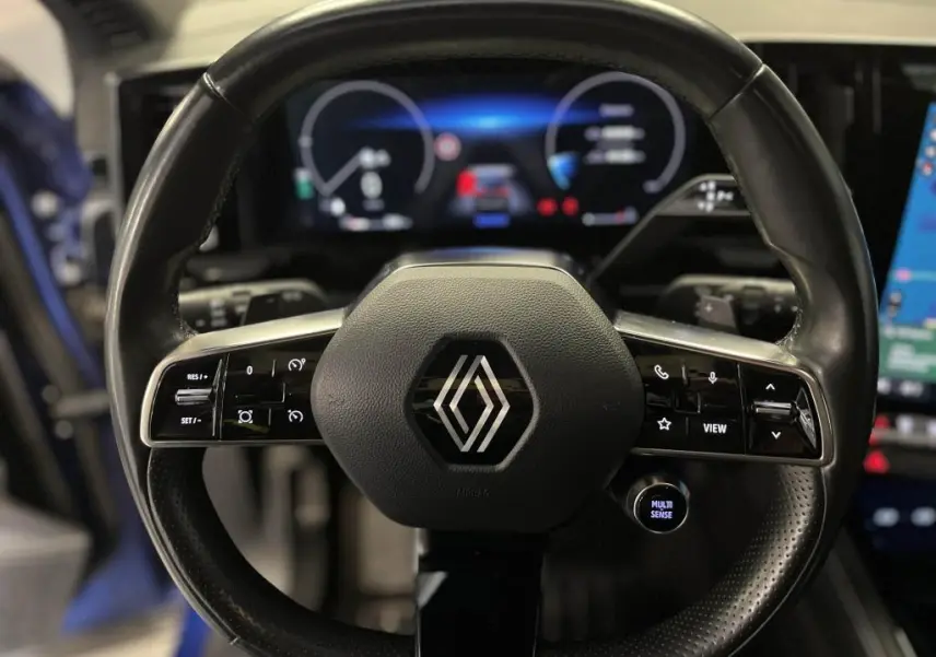 Volant cuir noir de Renault Austral 2023 avec commandes intégrées et tableau de bord numérique lumineux en arrière-plan.