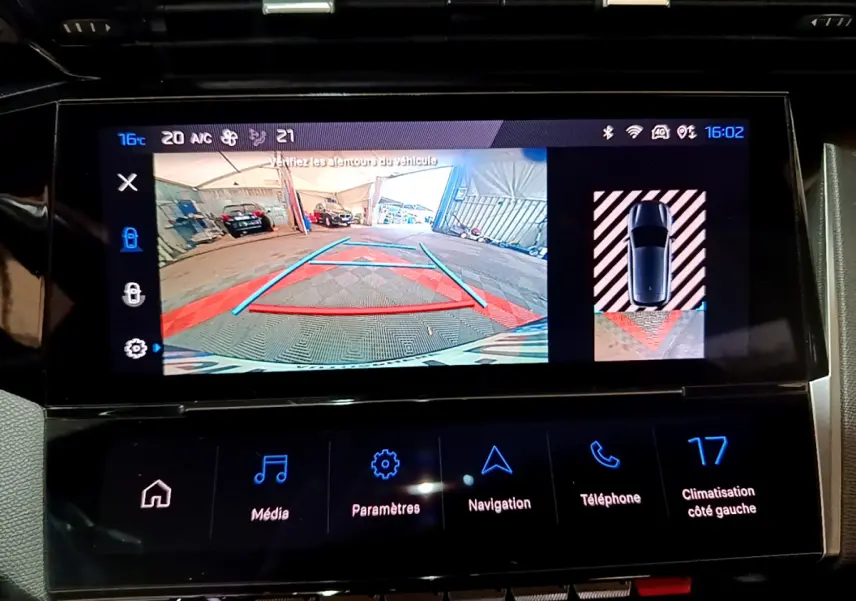 Écran tactile intérieur montrant la caméra de recul et l'aide au stationnement du Peugeot 308 PHEV blanc.