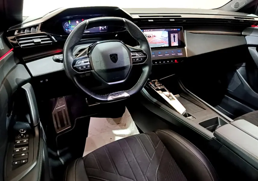 Intérieur Peugeot 308 PHEV 180 GT vu côté conducteur, tableau de bord moderne avec écran tactile et volant compact cuir.