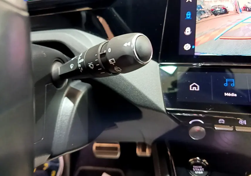 Gros plan sur la commande d’essuie-glace à gauche du volant dans l’habitacle noir de la Peugeot 308 PHEV GT 2022.