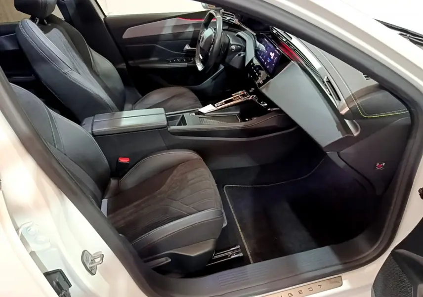Intérieur côté conducteur de la Peugeot 308 PHEV 180 GT blanc, avec sièges noirs et tableau de bord digital.