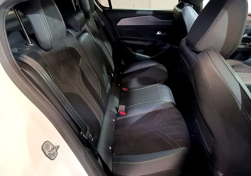 Vue côté gauche de l'habitacle arrière de la Peugeot 308 PHEV 180 E-EAT8 GT 2022 avec sièges noirs et surpiqûres vertes.