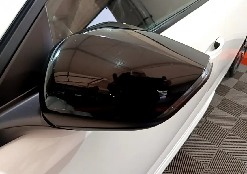 Rétroviseur noir brillant côté gauche d'une Peugeot 308 PHEV 180 E-EAT8 GT blanche vue en gros plan.