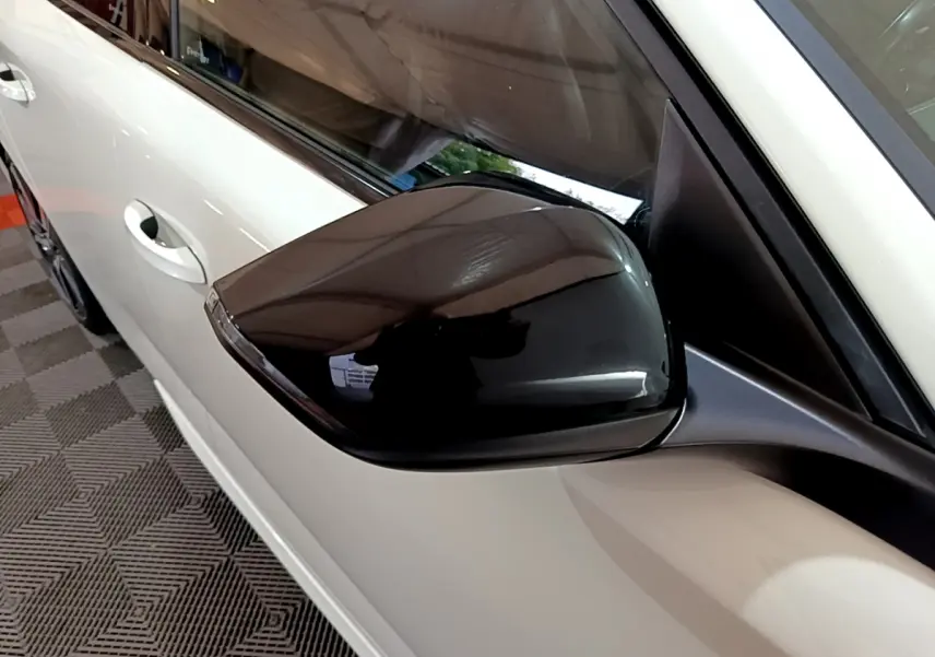 Gros plan sur le rétroviseur noir côté gauche d'une Peugeot 308 PHEV 180 E-EAT8 GT blanche de 2022.