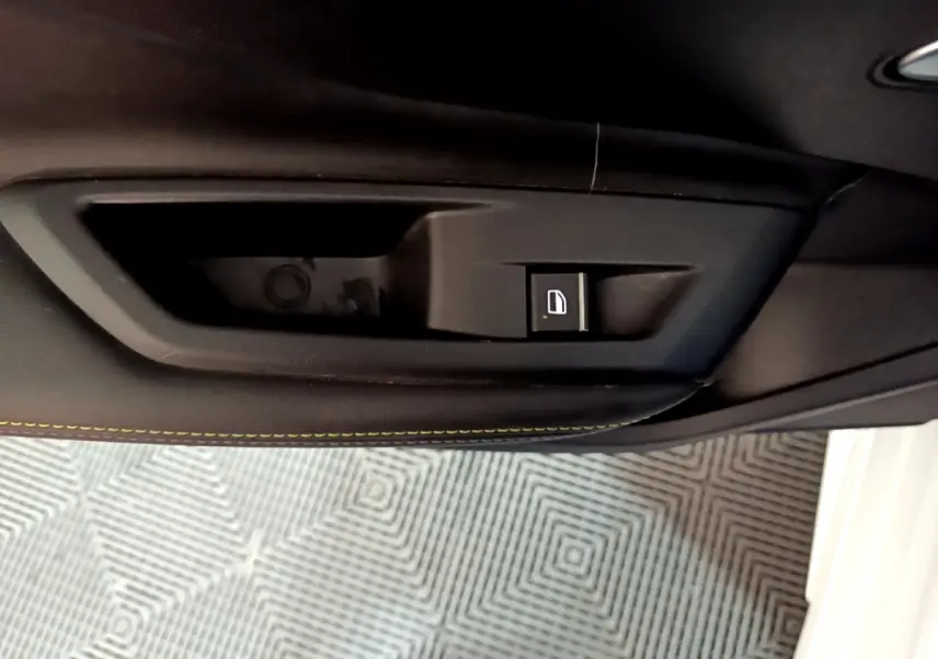 Bouton de verrouillage de porte noir sur la garniture intérieure côté conducteur d'une Peugeot 308 PHEV blanche.