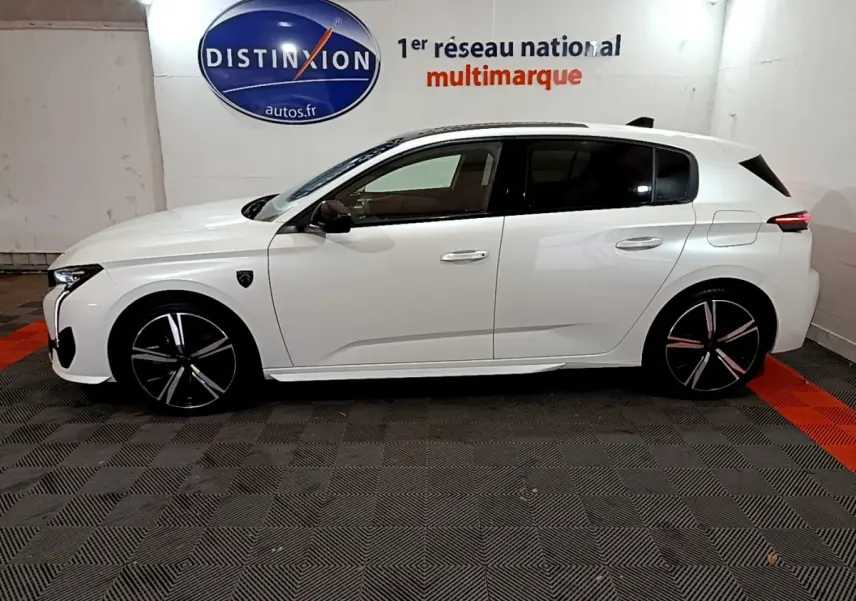 Profil côté gauche d'une Peugeot 308 PHEV 180 E-EAT8 GT blanche, avec jantes noires et détails modernes visibles.