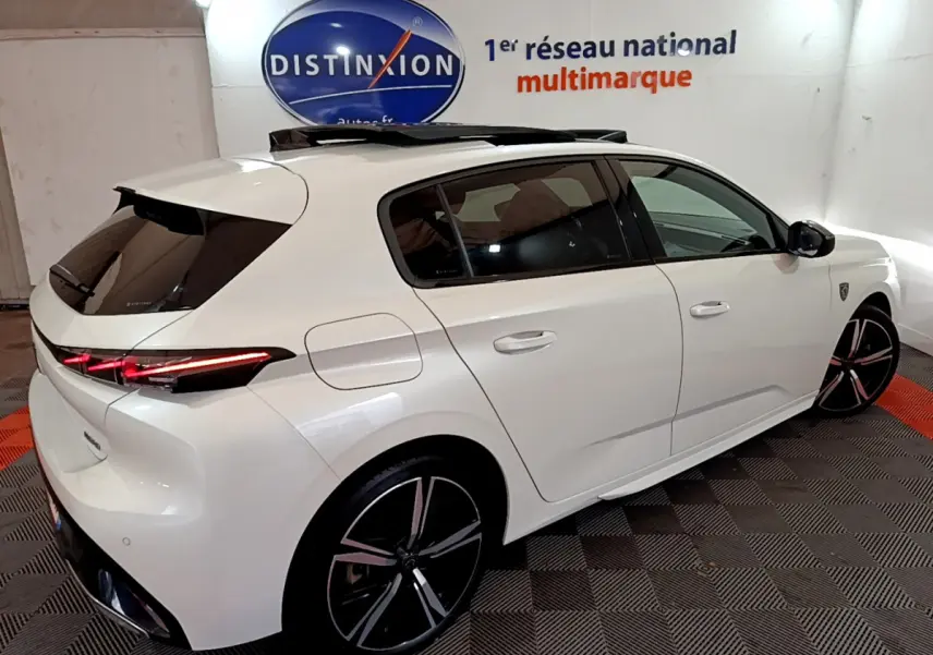 Peugeot 308 PHEV 180 GT blanc vue 3/4 arrière droit avec toit ouvrant et feux LED allumés.
