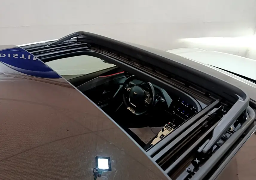 Vue plongeante sur l'intérieur noir d'une Peugeot 308 PHEV 180 E-EAT8 GT blanche avec toit ouvrant panoramique ouvert.