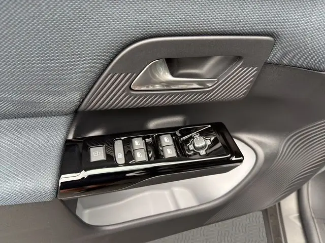 Gros plan sur la commande des vitres et rétroviseurs côté conducteur du Citroën C5 Aircross gris platinium, intérieur tissu bleu.