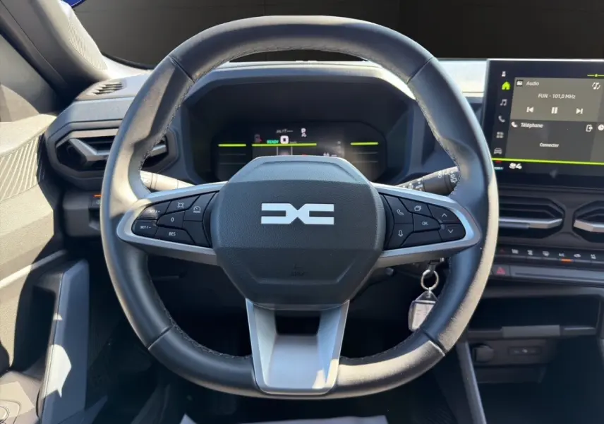 Volant cuir synthétique multifonctions au centre du tableau de bord du Dacia Duster gris foncé 2025, vue de face.