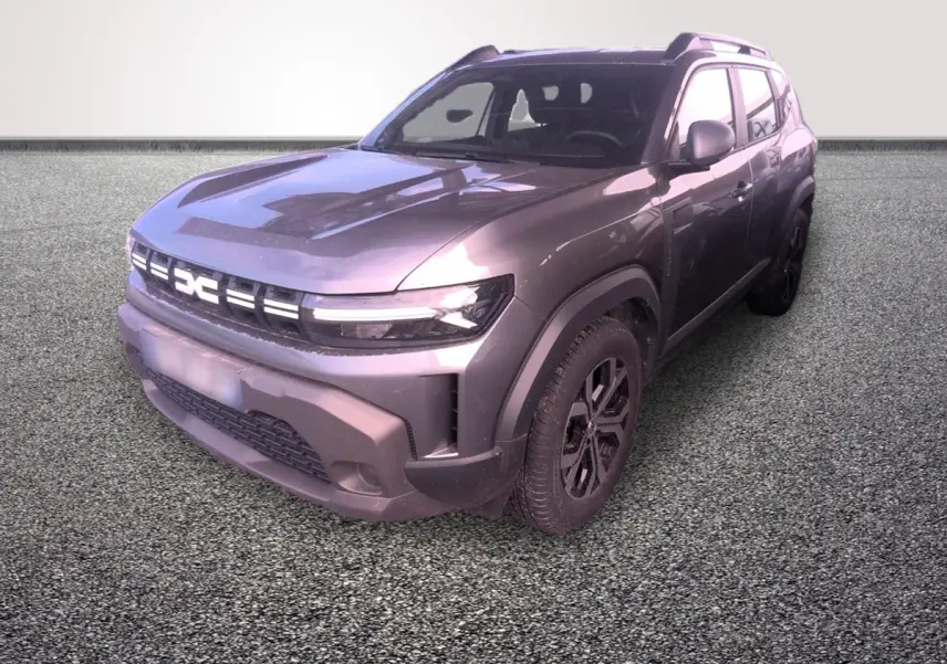 Dacia Duster gris foncé en 3/4 avant droit, avec calandre lumineuse et jantes noires distinctives.