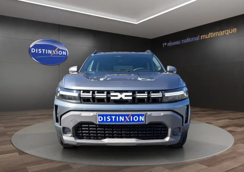Vue frontale d'un Dacia Duster Expression Hybrid 140 gris foncé avec calandre marquée et feux LED fins.