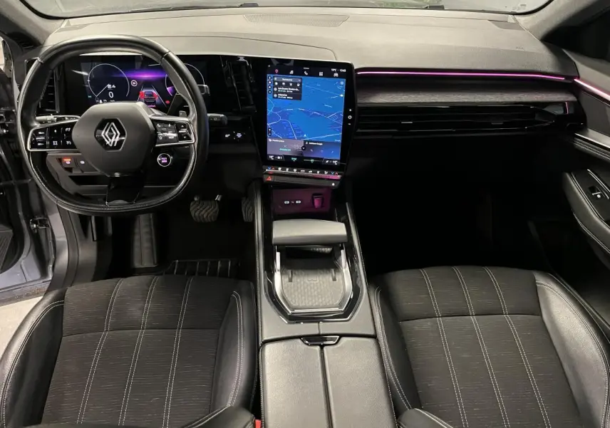 Intérieur avant du Renault Austral 2023, tableau de bord avec écran tactile vertical et éclairage d'ambiance violet.