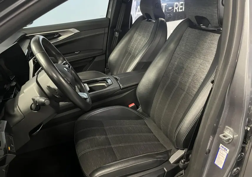 Vue intérieure côté conducteur du Renault Austral gris, sièges en simili-cuir noir avec surpiqûres argent et volant cuir.