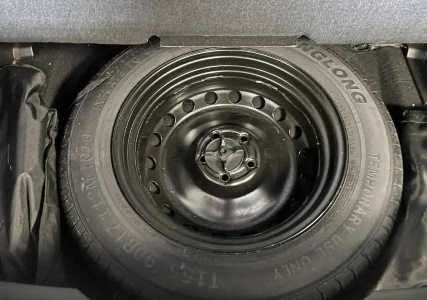 Gros plan sur la roue de secours galette noire du coffre d'un Renault Austral gris 2023.