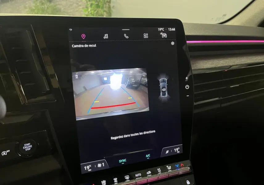 Écran central du Renault Austral 2023 affichant la caméra de recul avec ambiance lumineuse rose sur la planche de bord.