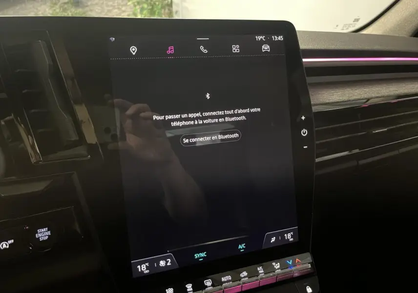 Écran tactile central du tableau de bord du Renault Austral 2023 avec ambiance lumineuse rose et inserts gris.