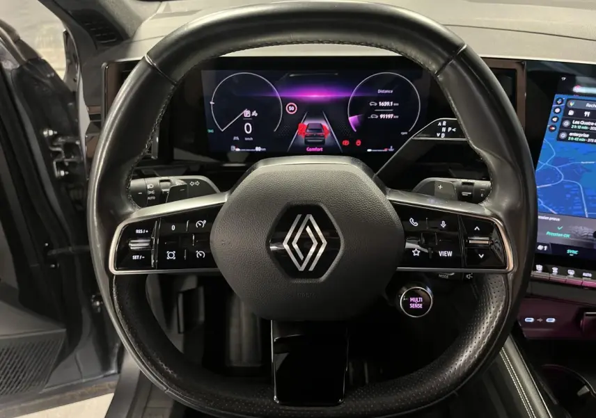 Vue frontale du volant cuir noir avec commandes intégrées du Renault Austral 2023, tableau de bord numérique et écran tactile visibles.