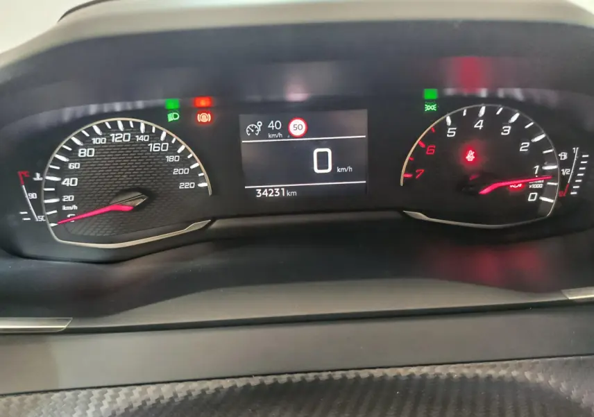 Tableau de bord de Peugeot 208 PureTech 100, affichage numérique central et compte-tours à aiguille, intérieur noir.