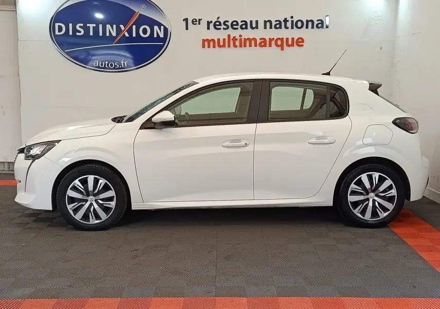 Profil côté gauche d'une Peugeot 208 blanche PureTech 100 S&S Active Business de 2020 en intérieur showroom.