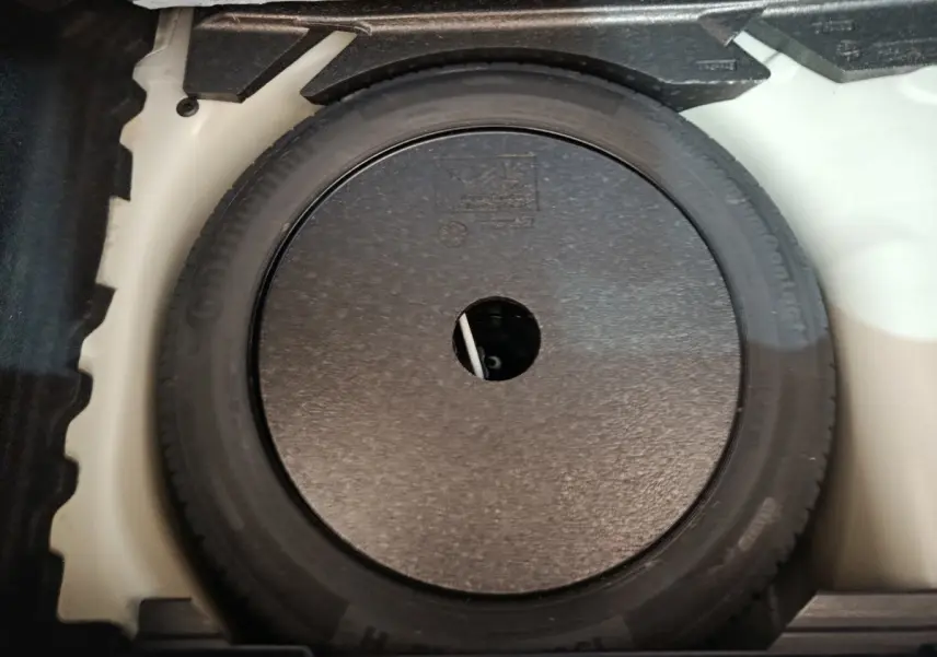 Vue plongeante sur la roue de secours noire dans le coffre blanc d'une Peugeot 208 PureTech 100 S&S Active Business 2020.