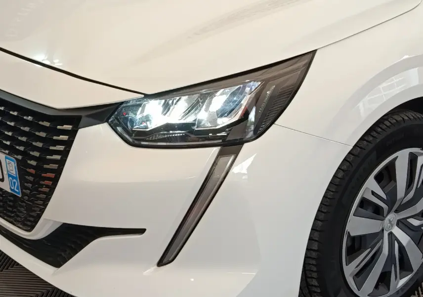 Gros plan sur l'avant droit blanc d'une Peugeot 208 2020 avec phares LED et jante alliage distinctive.
