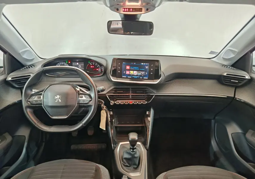 Vue frontale de l'intérieur noir du Peugeot 208 PureTech 100 S&S Active Business avec volant cuir et écran tactile central.