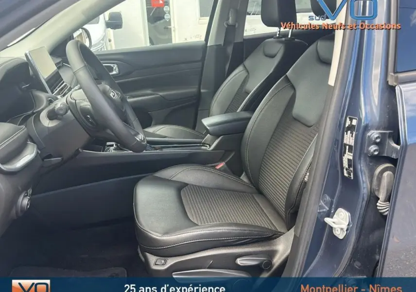 Vue intérieure côté conducteur du Jeep Compass bleu 2023, sièges en cuir noir avec accoudoir central et tableau de bord moderne.