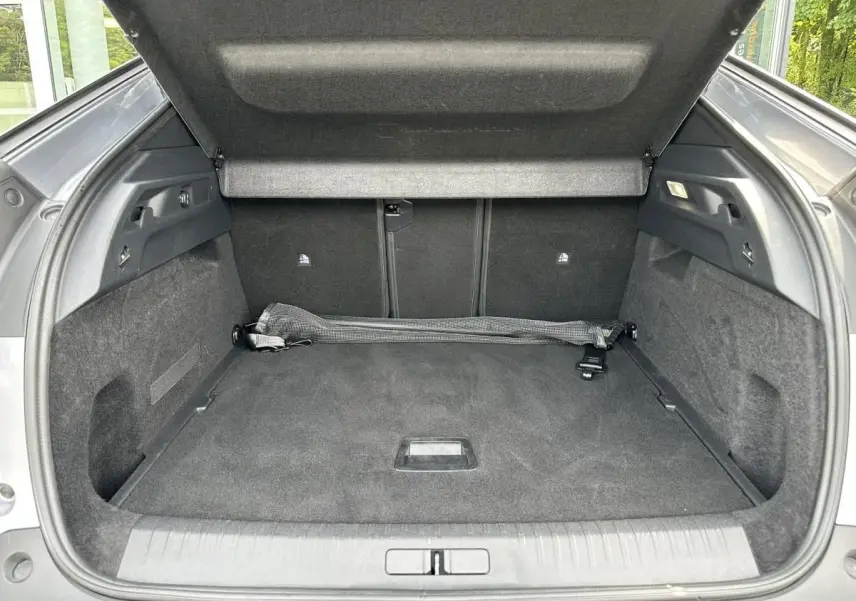 Coffre ouvert vu de l'arrière d'un Peugeot 3008 gris Artense, avec tapis et filet de rangement noir.