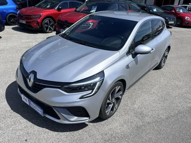 Renault Clio V gris métal vue 3/4 avant droit, avec calandre noire et jantes alliage distinctives RS Line.