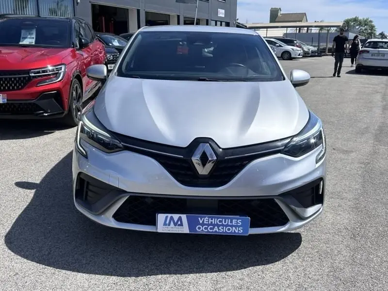 Vue de face d'une Renault Clio V gris métal 2022 version RS Line hybride, avec calandre noire distinctive et phares LED.