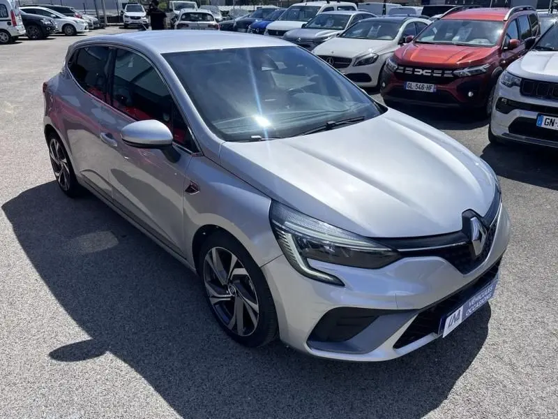 Vue 3/4 avant droite d'une Renault Clio V gris métal RS Line avec jantes alliage et calandre distinctive.