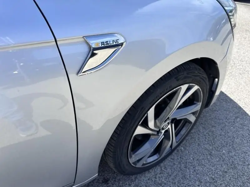 Détail du côté avant droit d'une Renault Clio V gris métal avec badge RS Line et jante alliage distinctive.