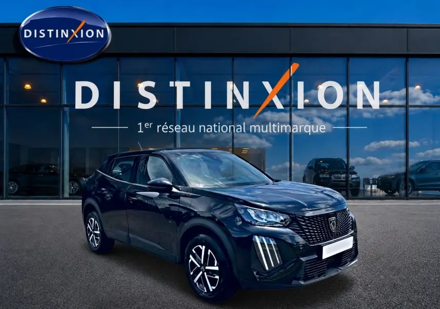 Peugeot 2008 noir en 3/4 avant droit, avec calandre distinctive et feux LED verticaux, devant vitrine Distinxion.