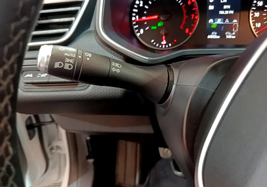 Gros plan sur la manette des phares et clignotants du tableau de bord d'une Renault Clio Business blanche de 2021.