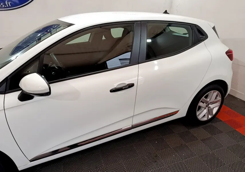 Profil côté gauche d'une Renault Clio Business blanche, mettant en valeur la ligne épurée et les jantes alliage.
