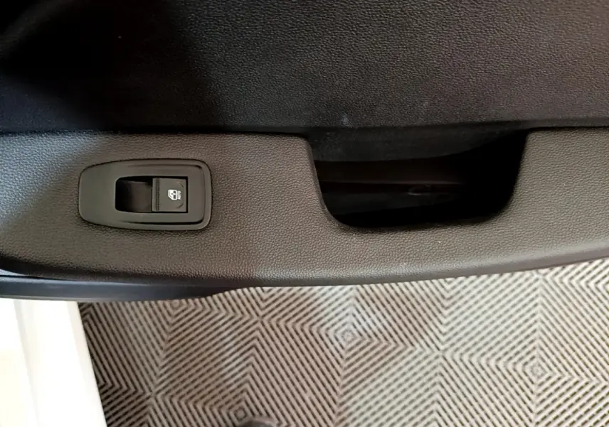 Détail de la commande de lève-vitre sur la porte intérieure noire d'une Renault Clio Business blanche de 2021.