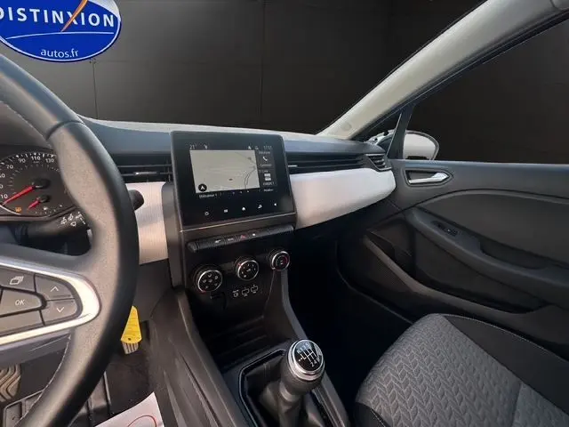 Intérieur avant droit de la Renault Clio V gris Highland, volant multifonction, écran tactile et levier de vitesse manuel visible.