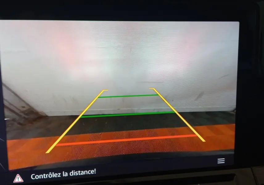 Affichage caméra de recul avec lignes de guidage colorées sur fond de mur blanc et sol carrelé, intérieur Volkswagen Golf 2022.