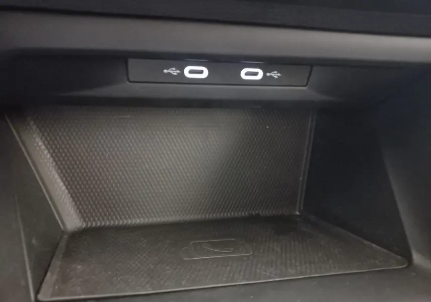 Gros plan sur la zone de recharge sans fil et ports USB du Volkswagen Golf 1.5 bleu, intérieur noir.