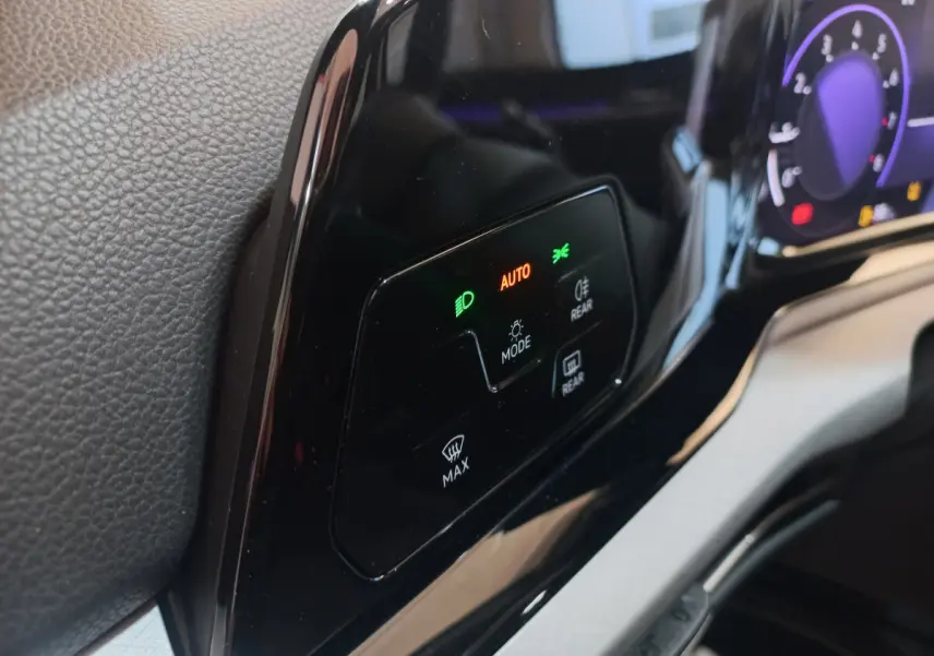 Détail du tableau de bord noir brillant de la Volkswagen Golf 2022, avec commandes d'éclairage et affichage digital.