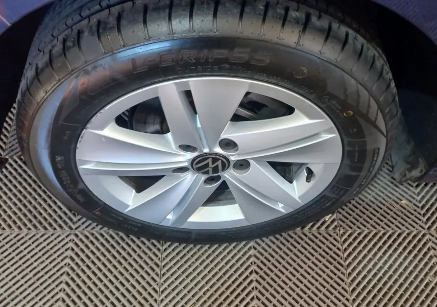 Gros plan sur la roue avant droite d'une Volkswagen Golf bleue, jante alliage argentée avec logo VW central.